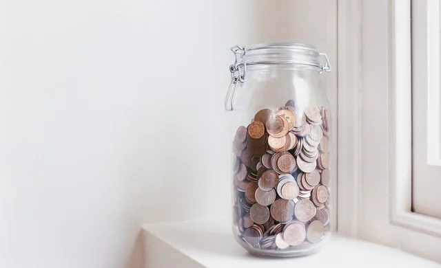 Glass jar of pennies on a windowsill