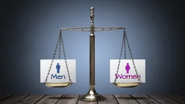 balanced scales with a sign with men on one side and women on the other