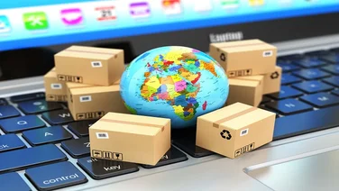 Small globe on a keyboard surrounded by small brown packages