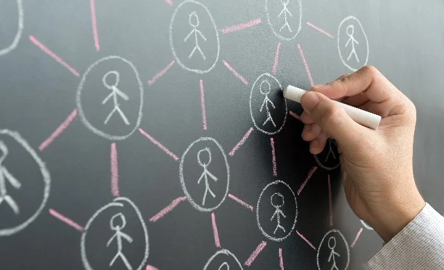 Mid shot of a hand drawing chalk figures on a blackboard