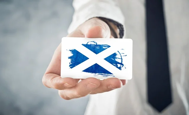 Business man holding a small card denoting Scottish flag
