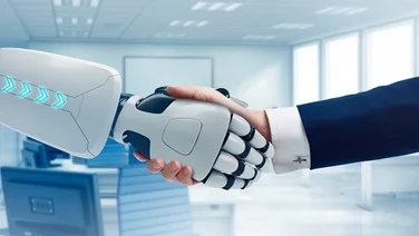 Mid-shot of a robot hand shaking a business man's hand.