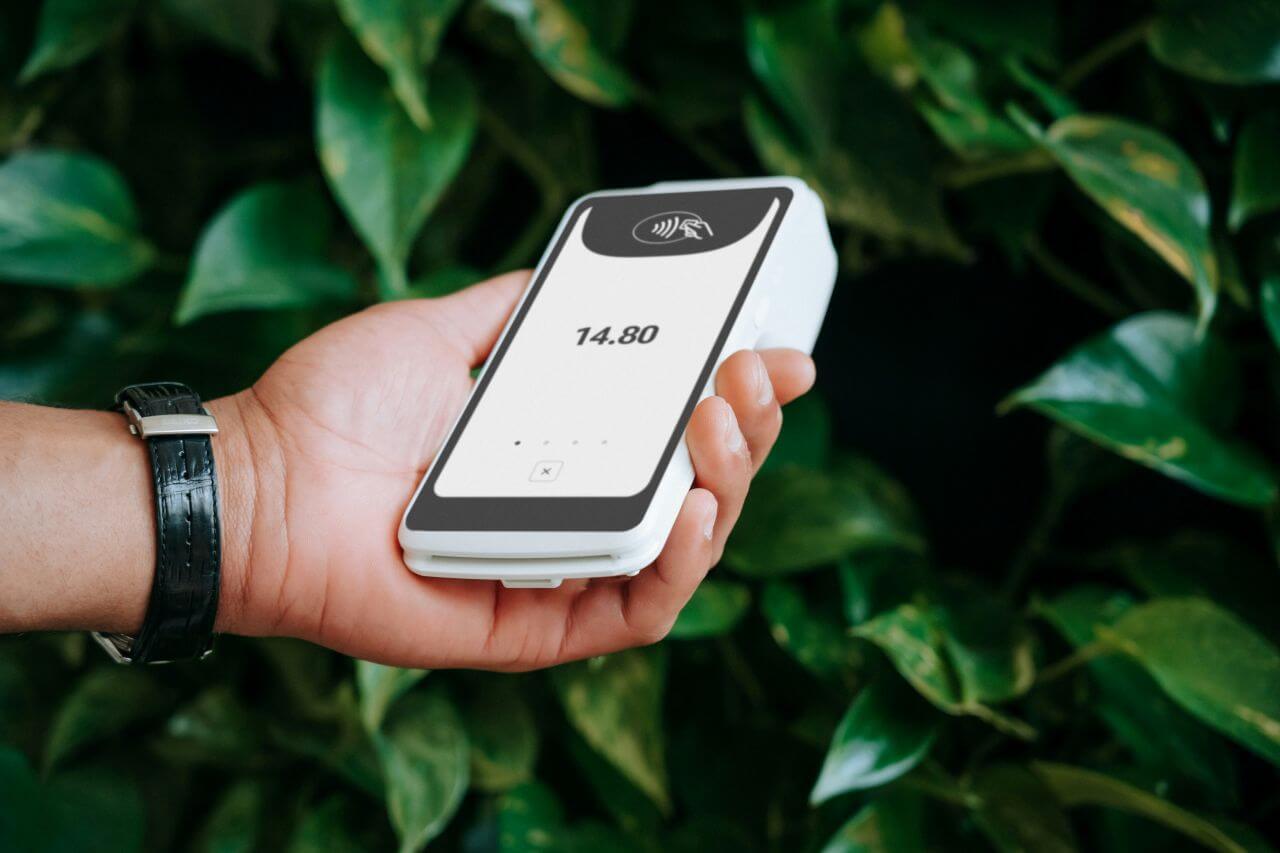 A persons hand holds up the SumUp Terminal.