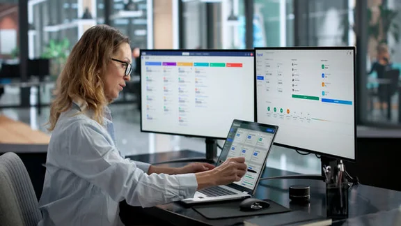 Office worker performing HR duties on 3 monitors