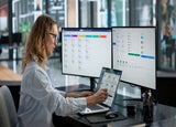Office worker performing HR duties on 3 monitors