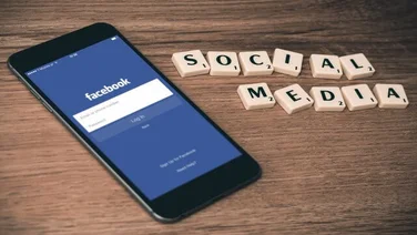 mobile on a table next to scrabble letters spelling out social media