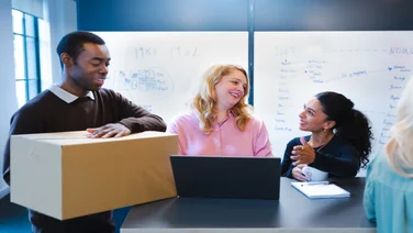 Man with packaging, talking to colleagues