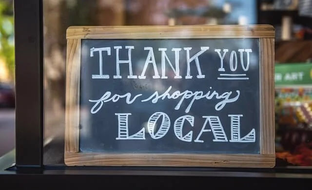 blackboard sign on shop door saying "thank you for shopping local"