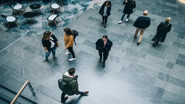 Crowd of people in modern office building hallway. Business people walking across office lobby.