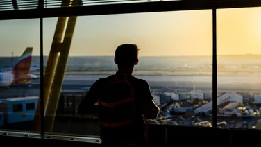 Man views the sunset out the window at Heathrow airport with British Airways planes on the runway