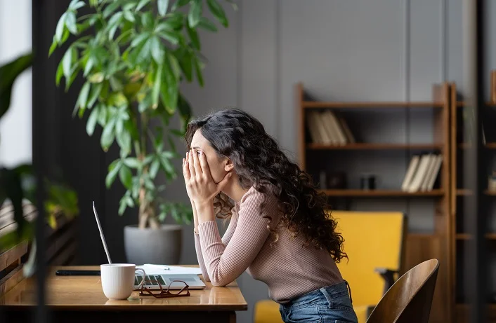 Exhausted female office worker struggling through task, tired overworked female employee