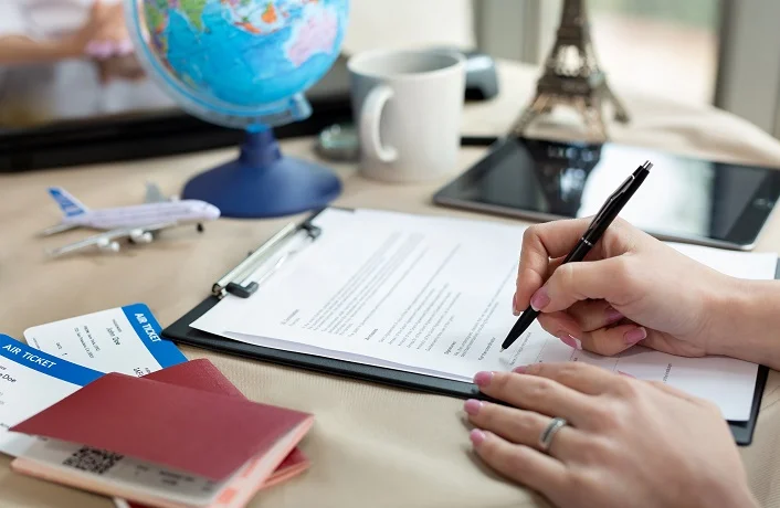 A female travel agent in the office signs a contract, close-up.