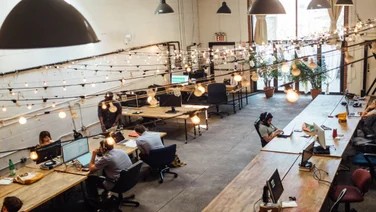 An industrial-looking co-working space filled with desks and people
