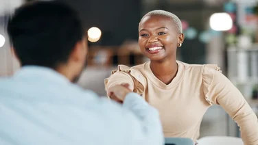 Black, female woman shaking hands with white male to seal an agreement
