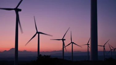 a series of wind turbines against a sunset