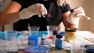 Woman making epoxy resin arts and crafts. Creation of handmade coaster.