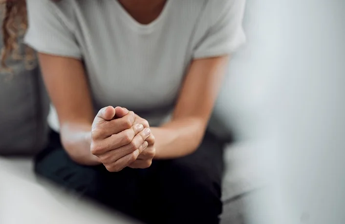 Hands, psychology and mental health with a woman in a therapy session for grief counseling after loss. Anxiety, stress or depression with a female patient feeling nervous in a clinic for support.