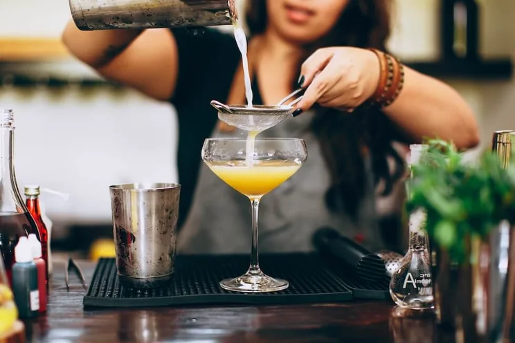 a female bartender pours a cocktail