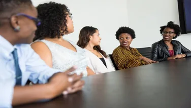 a group of businesswomen speaking at a table