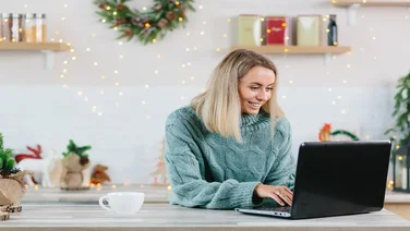 Business woman working at home on laptop during Christmas and New Year, happy and successful completes a big project