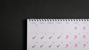Calendar with ticks and crosses, depicting four day work week concept. Copy space.