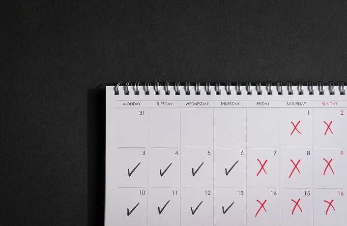 Calendar with ticks and crosses, depicting four day work week concept. Copy space.