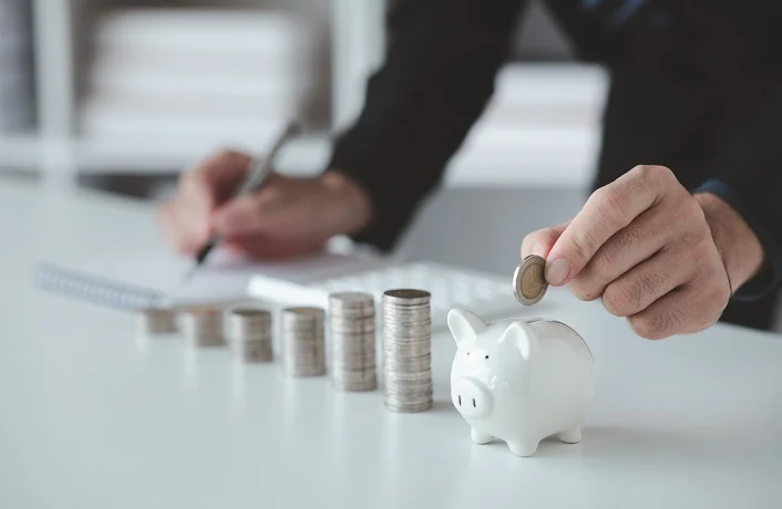 Person with pile of coins and piggy bank, money saving concept for future use and financial stability, salary management, personal finance, investment savings.