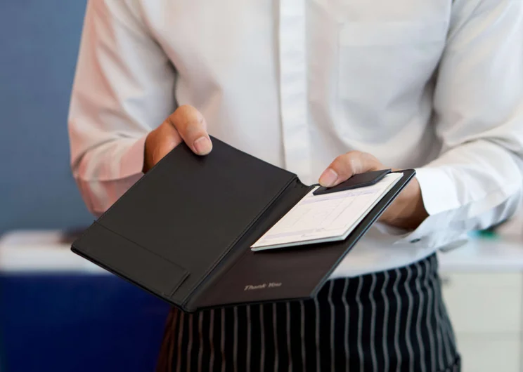 Waitress holding out a bill to a customer to add a service charge