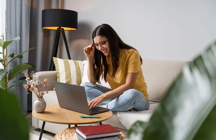 Back to study. Happy student doing her work at home on laptop in a cosy room.