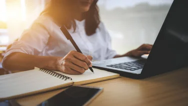 Professional doing research on a laptop and making notes