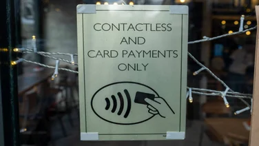 Sign in a business's window stating "contactless and card payments only"