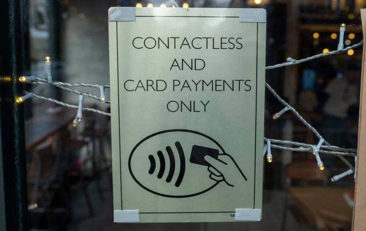 Sign in a business's window stating "contactless and card payments only"