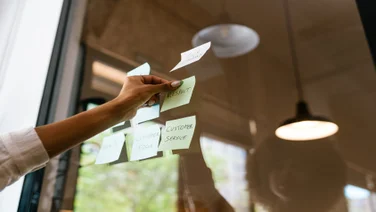A single hand sticking written post it notes onto a window.