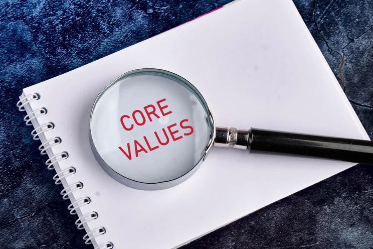 Plain white notebook with a magnifying glass over the words "core values"
