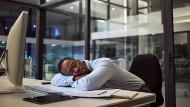 Man sleeping at office desk during work day