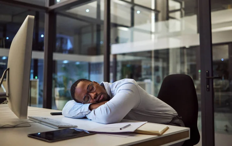 Man sleeping at office desk during work day