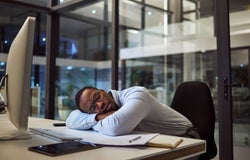 Man sleeping at office desk during work day