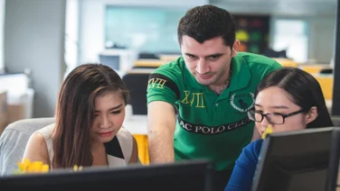 Young people gathered at a computer in a work environment