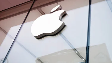 A close up shot of the outside of an Apple office with its logo displayed on front.