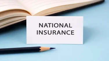 A single white card sitting upon a blue table with the words "National Insurance" read on it.