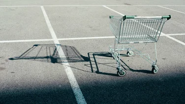 An empty shopping cart casts a shadow over an empty car park
