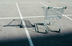An empty shopping cart casts a shadow over an empty car park