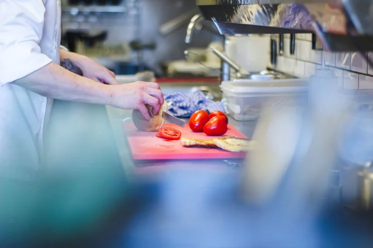 A chef prepares fresh vegetables on a chopping board