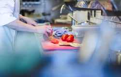 A chef prepares fresh vegetables on a chopping board