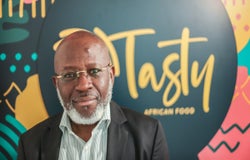 Image of Michael Olaleye, founder and managing director of Tasty African Food, in front of a blurred sign reading Tasty African Food