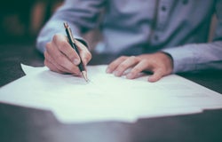 A person is signing a contract with a pen.