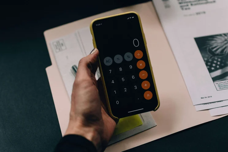 A hand holds a smartphone with a the calculator app open.
