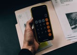 A hand holds a smartphone with a the calculator app open.