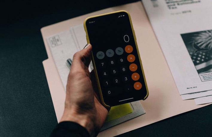 A hand holds a smartphone with a the calculator app open.