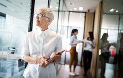 A woman standing in the corridor of an office.